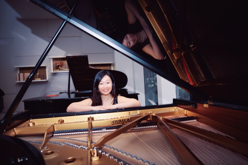 Khew Yun Zhen, founder of Happy Feet, smiling behind the open lid of a grand piano.